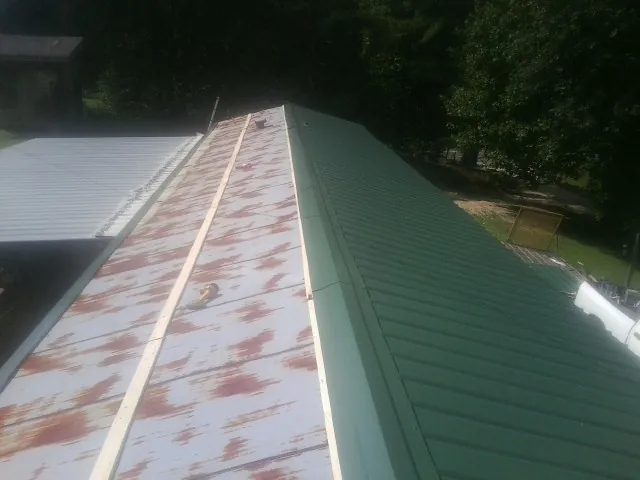 Old rusted panels beside newly installed green metal roofing — Wind Damage Roof Repair by Roofing Brothers in Dry Run