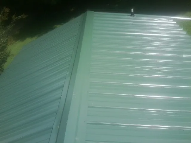 New green metal panels meeting at the ridge of a roof — Flat Roof Repair work by our crew in Dry Run