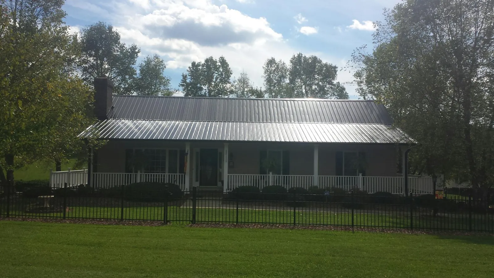 Gray metal roof on a brick ranch with a full width front porch — Gutter Guard Installation work by our crew in Dry Run