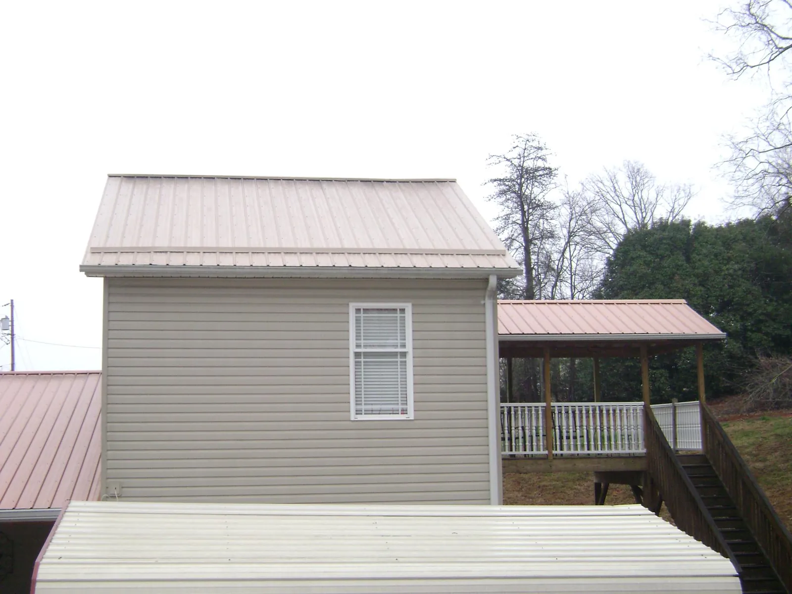 Tan metal roofs on a two story addition and attached porch, from a Roof Replacement job in Dry Run