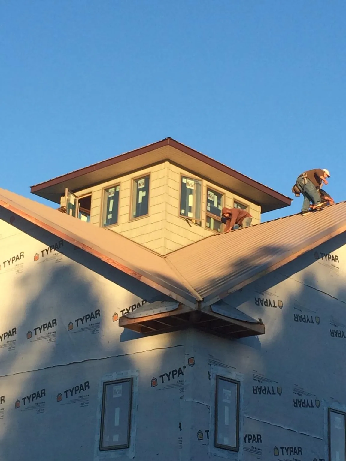 Roofers working around a rooftop cupola on a new metal roof at sunset — Roof Waterproofing in Dry Run by Roofing Brothers